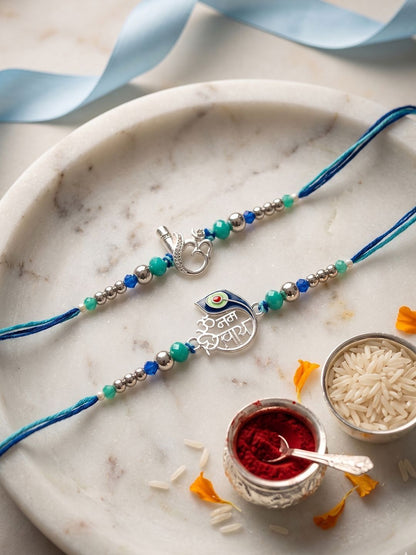 Dhiyona Set Of 2 Silver Toned Beaded Religious Thread Rakhi With Roli Chawal Chandan Mishri